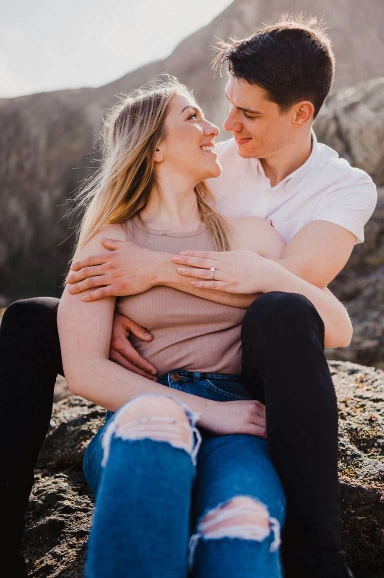 Photo of the happy couple sitting at Holywell bay during an engagement shoot celebrating their Proposal at Holywell Bay, Cornwall, UK