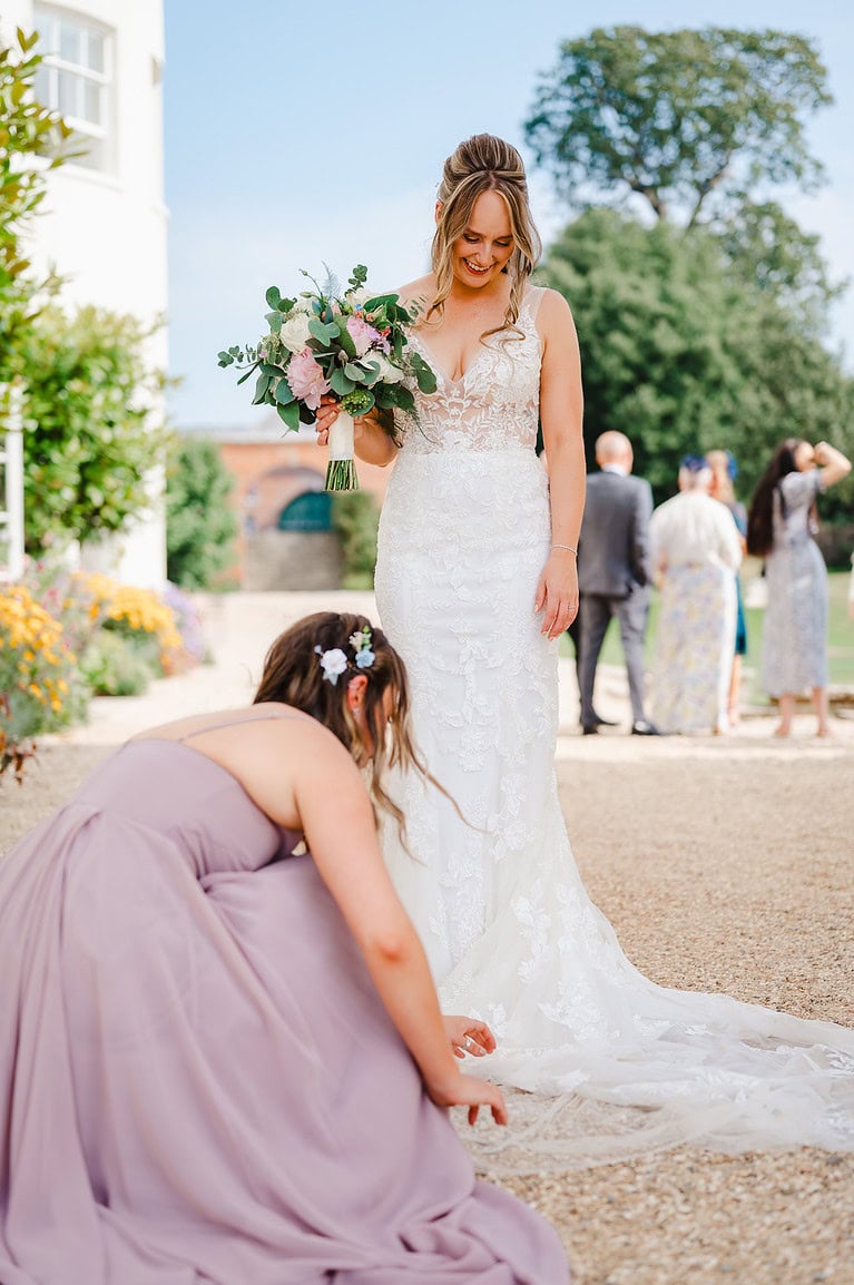Ultimate Wedding Photography Top Tips - Bridesmaid helps bride with wedding dress