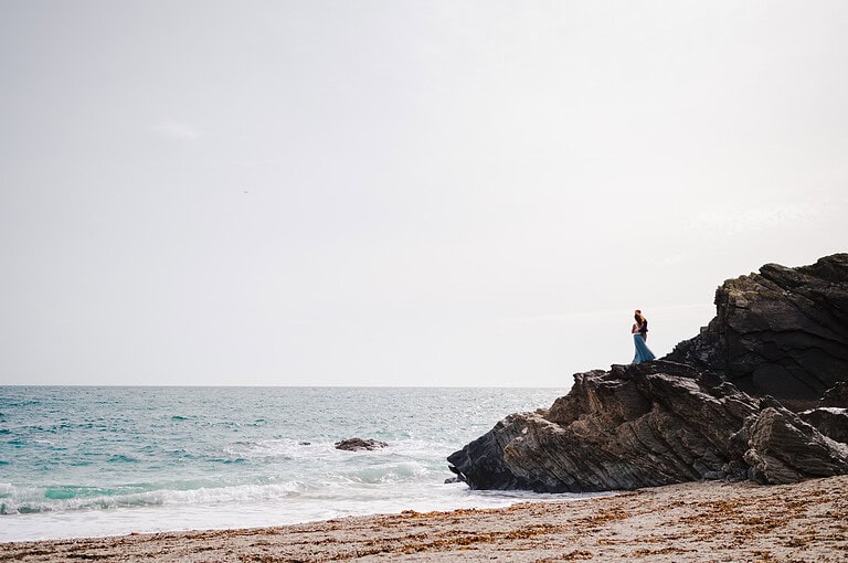 Couple stand on rocks looking out to sea on their Cornwall wedding - Ultimate Wedding Photography Top Tips