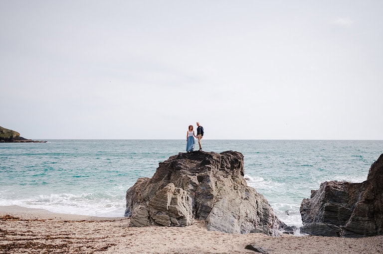 Couple standing on rocks at beach in St Austell, Cornwall - Best Places To Elope In Cornwall