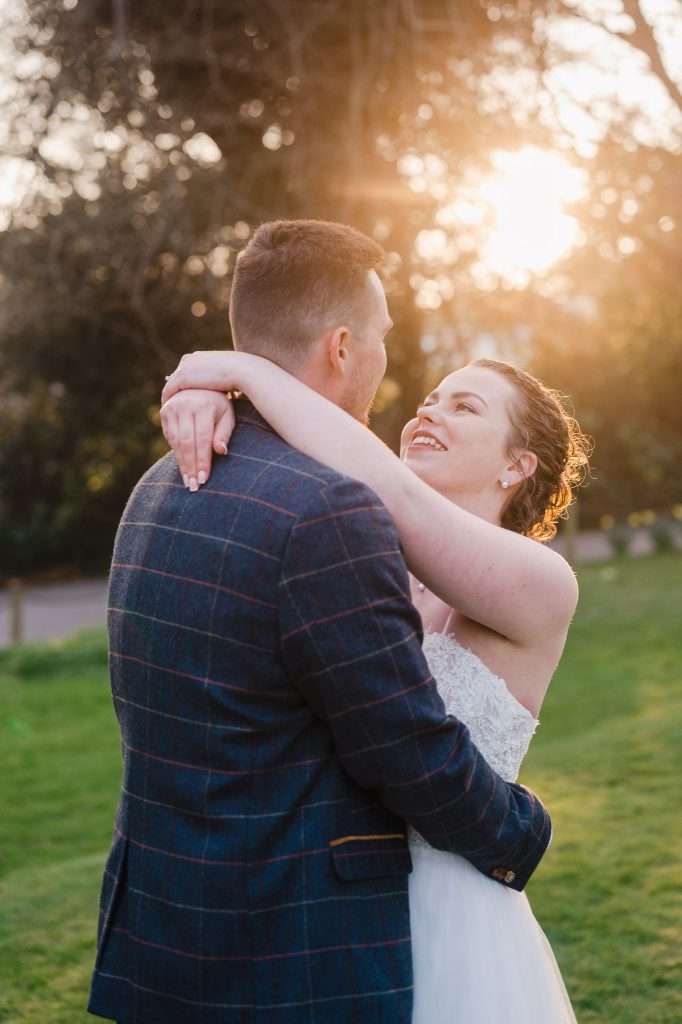 Bride looking up towards groom as the sun sets behind them - Wedding Photographer: How To Choose The Right One For You?