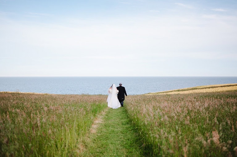 Wedding couple walking towards the sea over St Mawes, Cornwall - Summer Wedding Ideas o