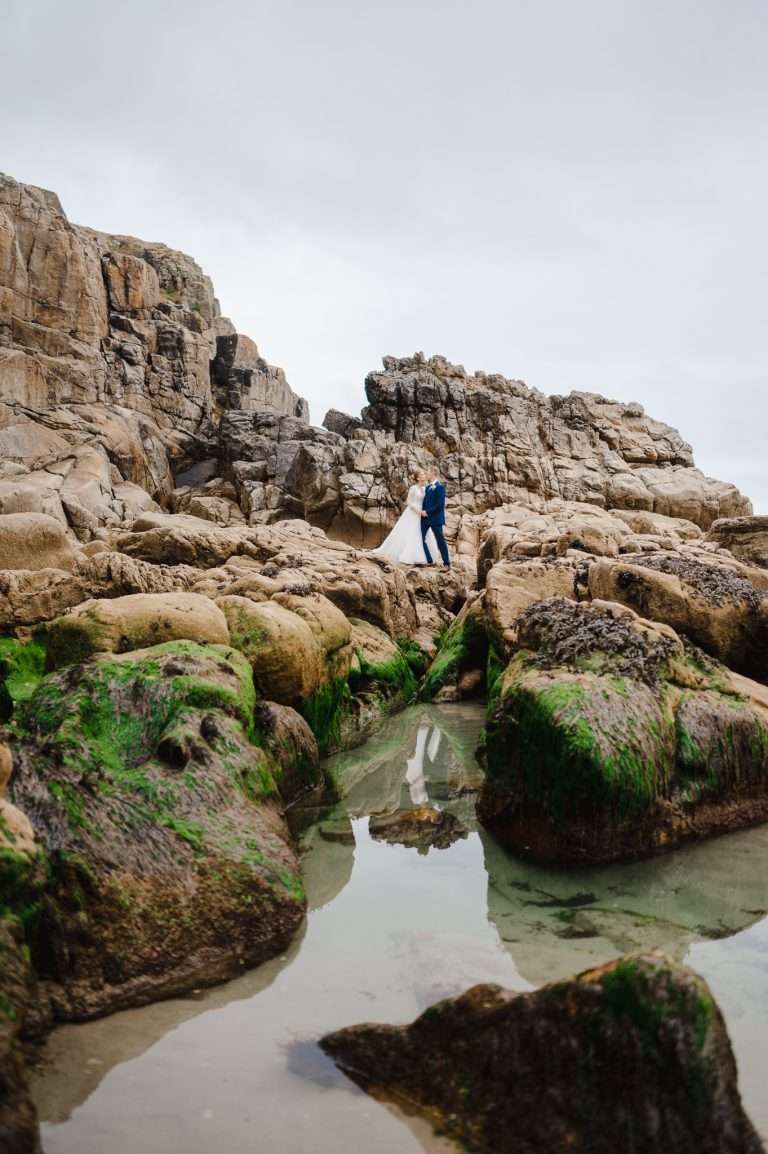 Wedding Couple standing on the rugged coastline by Rinsey, Cornwall - How To Pick Your Perfect UK Wedding Venue - Your Ultimate Guide