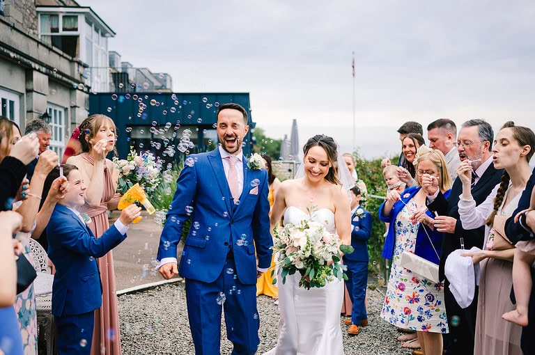Happy guests and bride and groom as they leave to their Wedding Bubble exit