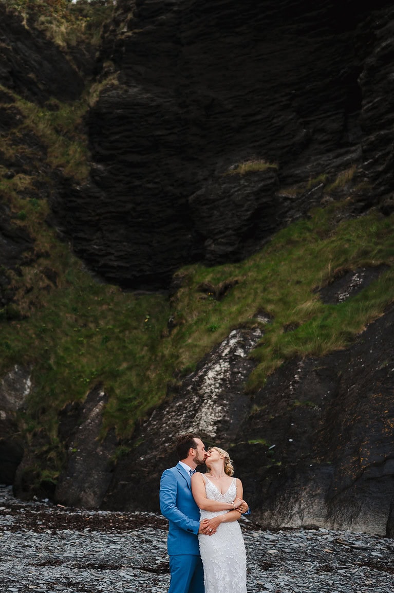 Wedding couple beneath grass covered dramatic rock face - 6 Creative Wedding Invitation Trends