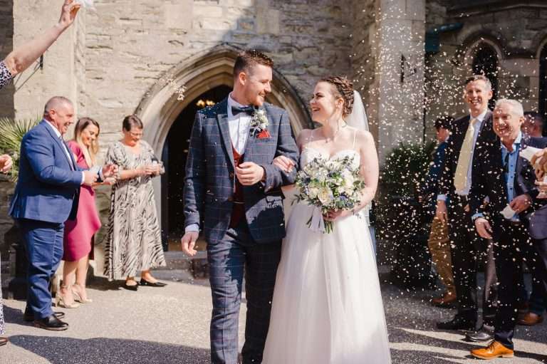 Wedding confetti thrown over the couple as they glance at each other - Your Ultimate Guide To Craft Your Wedding Day Timeline Part Two