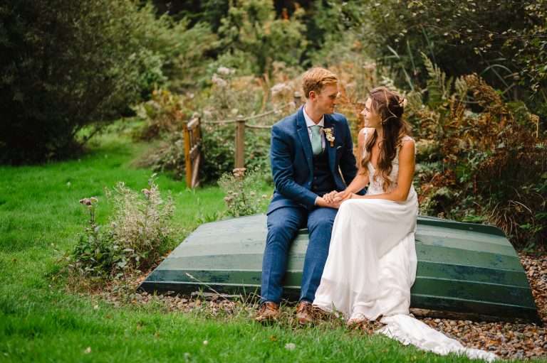 Couple sitting on turned over boat as they look into each others eyes - 7 Wedding Photos You Need To Put On Your Photography List