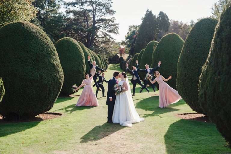 Bridal party jumping out of hedgerow to create a an amazing bridal party portrait - 25 Creative Wedding Planning Tips to Plan Your Dream Wedding