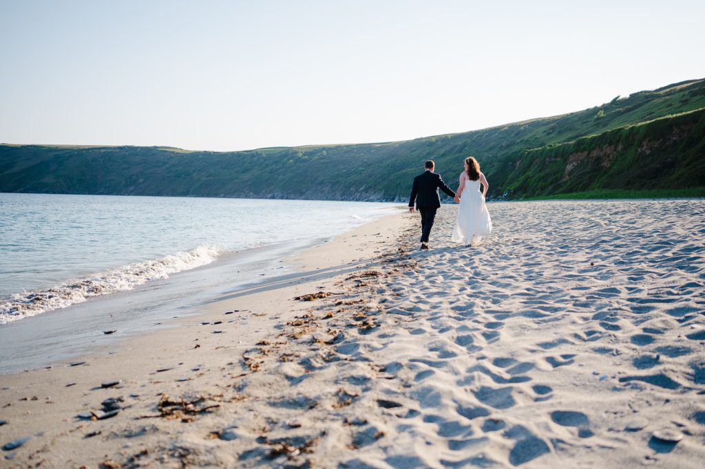 Wedding couple walking along a beautiful sandy beach in Cornwall