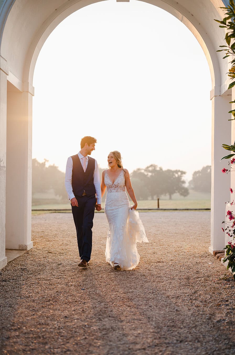 Happy Couple walk through the archway at a stunning wedding venue in Exeter by Exeter Wedding Photographer Jake Timms Photography