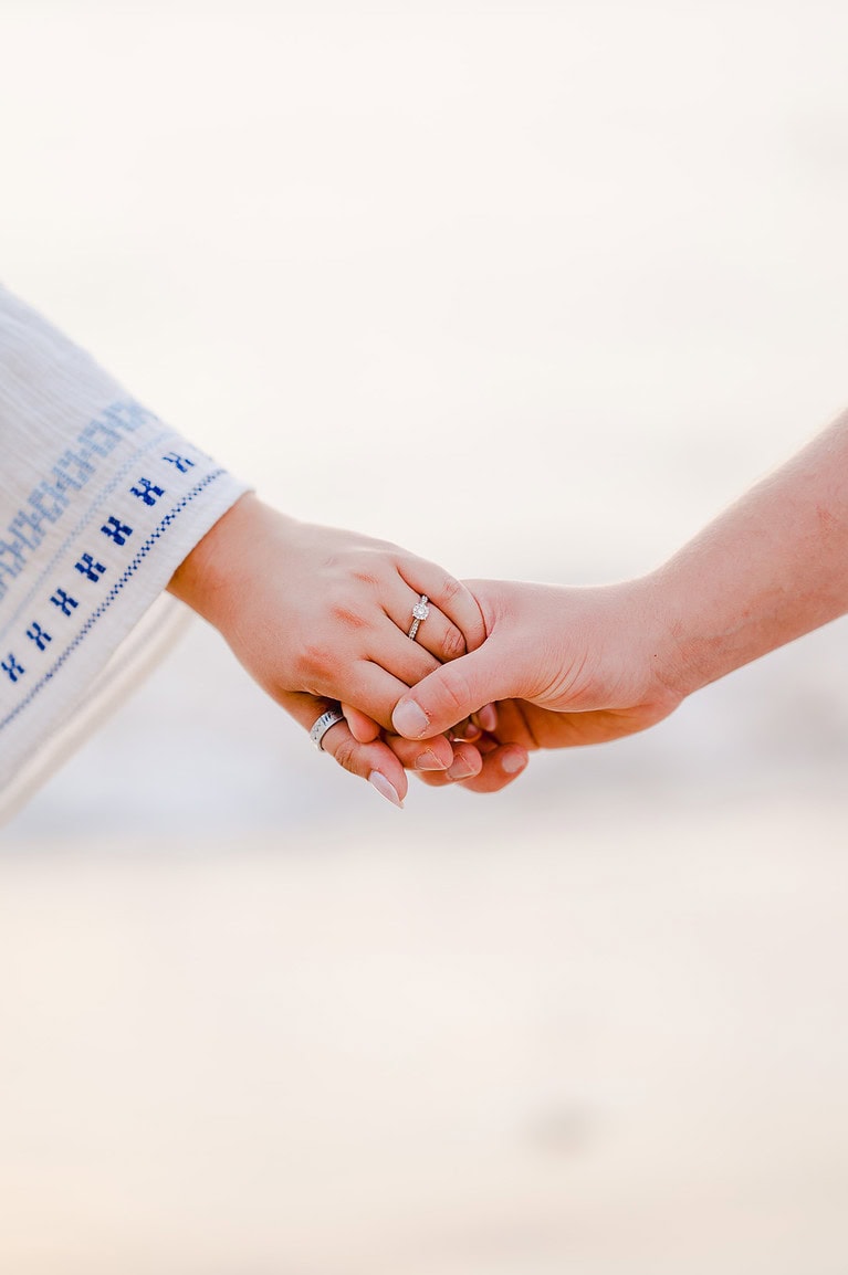 Holding hands, showing off the beautiful engagement ring