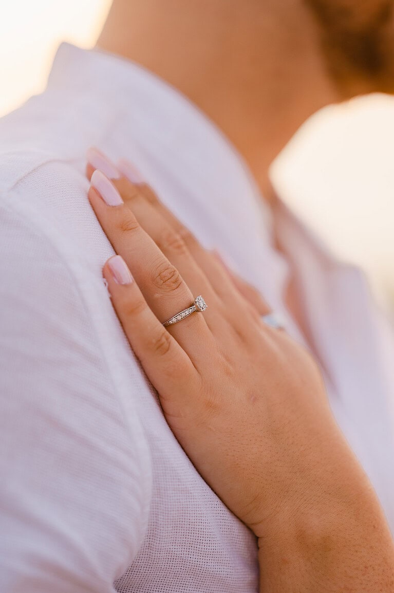 Focusing in on the engagement ring as she places her hand on his chest