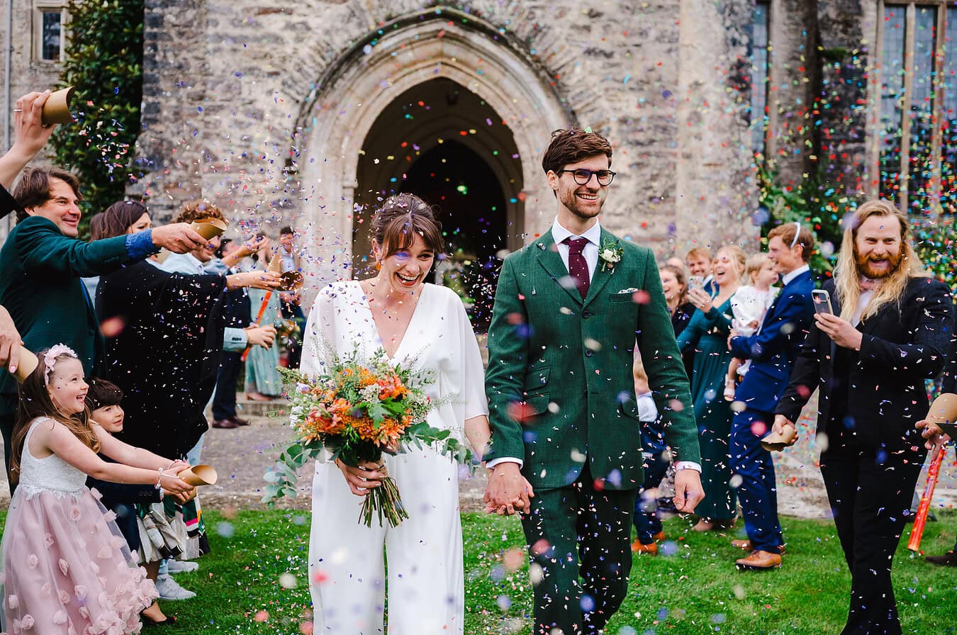 Wedding confetti being thrown all over couple as they walk down the confetti aisle outside darlington hall - Devon Wedding Photographer