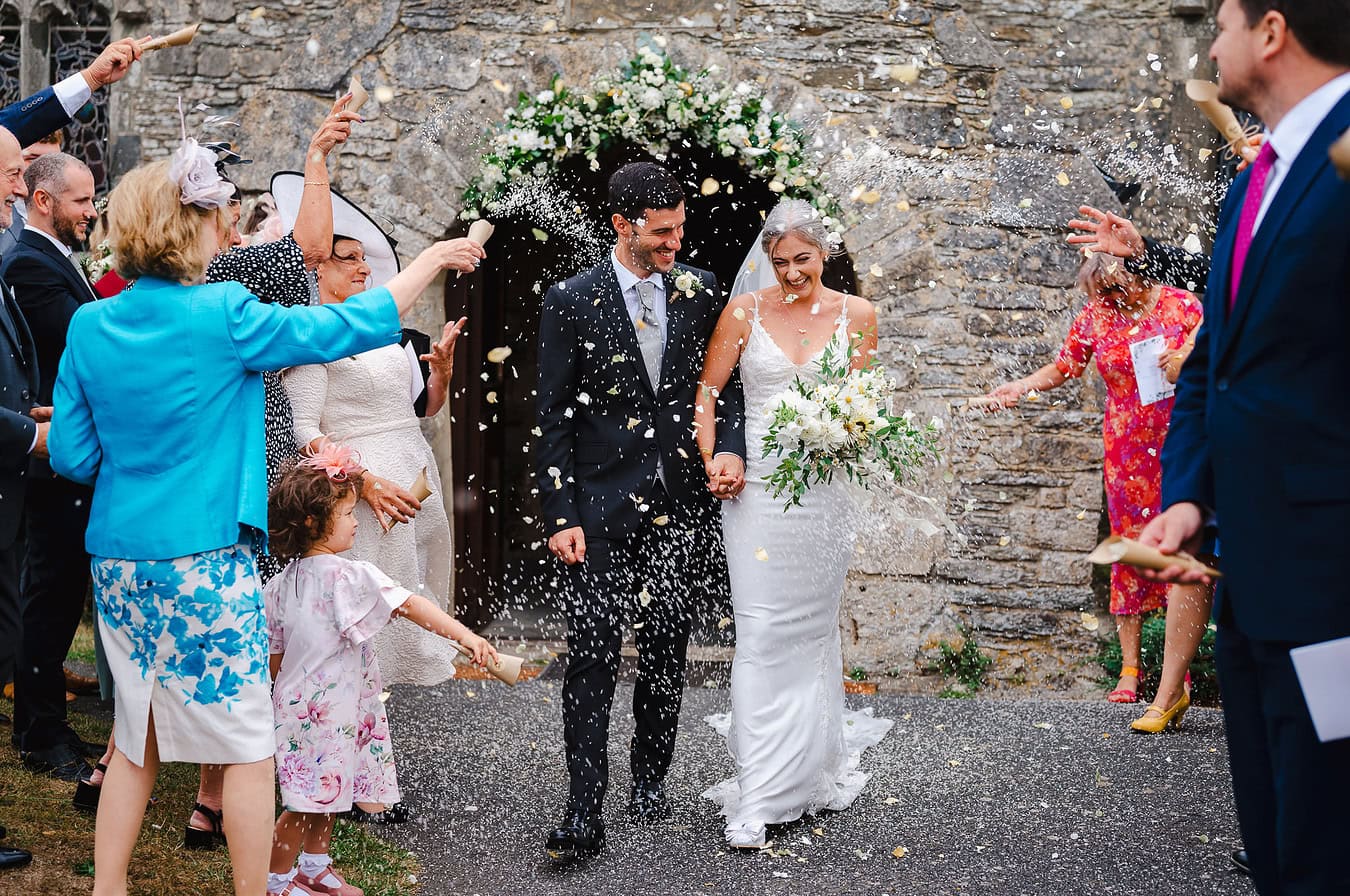 Covered in confetti as the happy couple leave their Church ceremony in Cornwall - Cornwall Wedding Photographer Wedding Portfolio