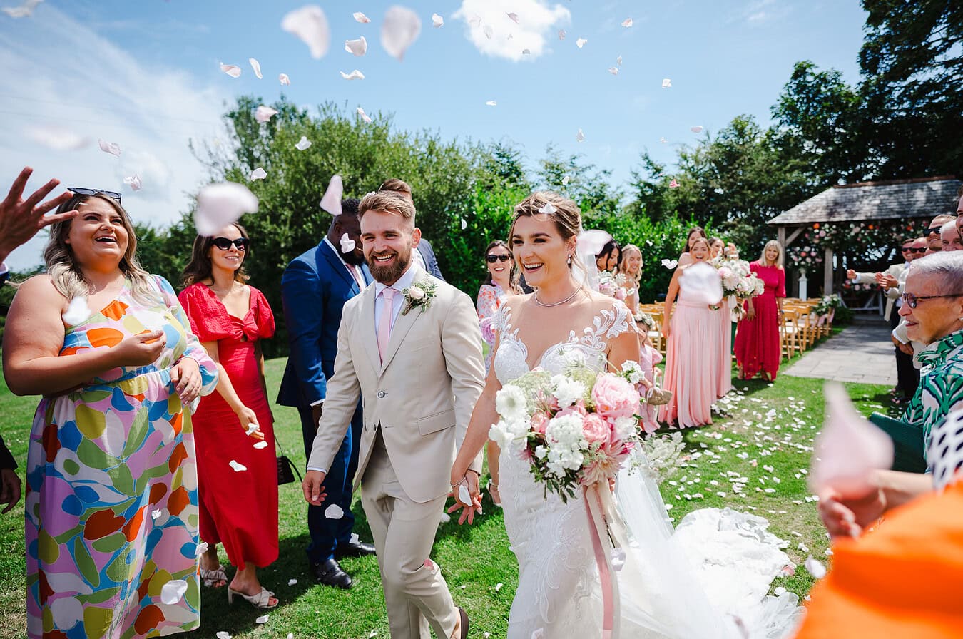 Full of laughter as the happy couple walks down the wedding confetti aisle at Trevenna