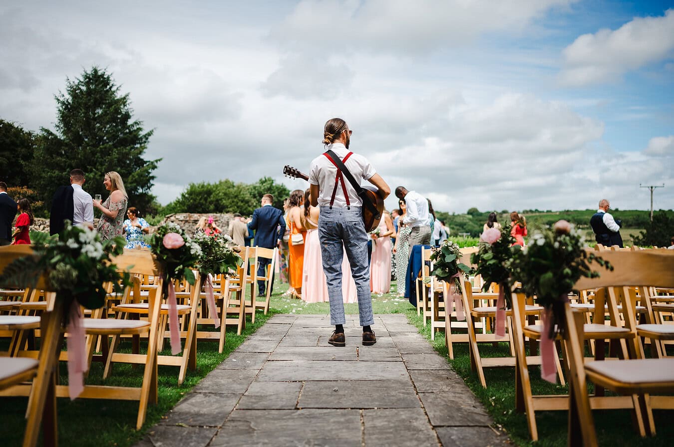 Guitar man standing on his own playing the guitar to all of the wedding party