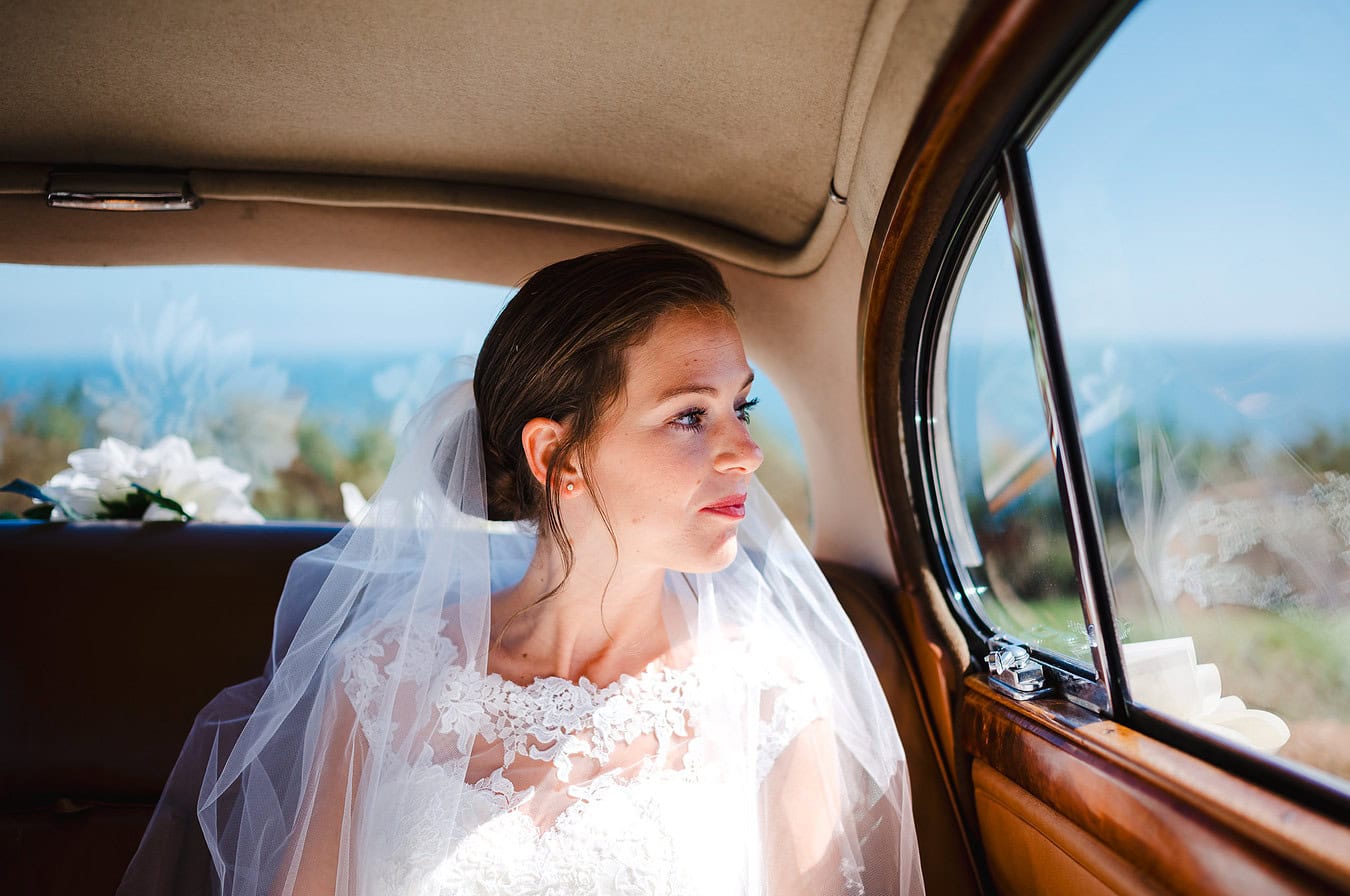 Bride looking out of her classic car waiting for the groom to open the door