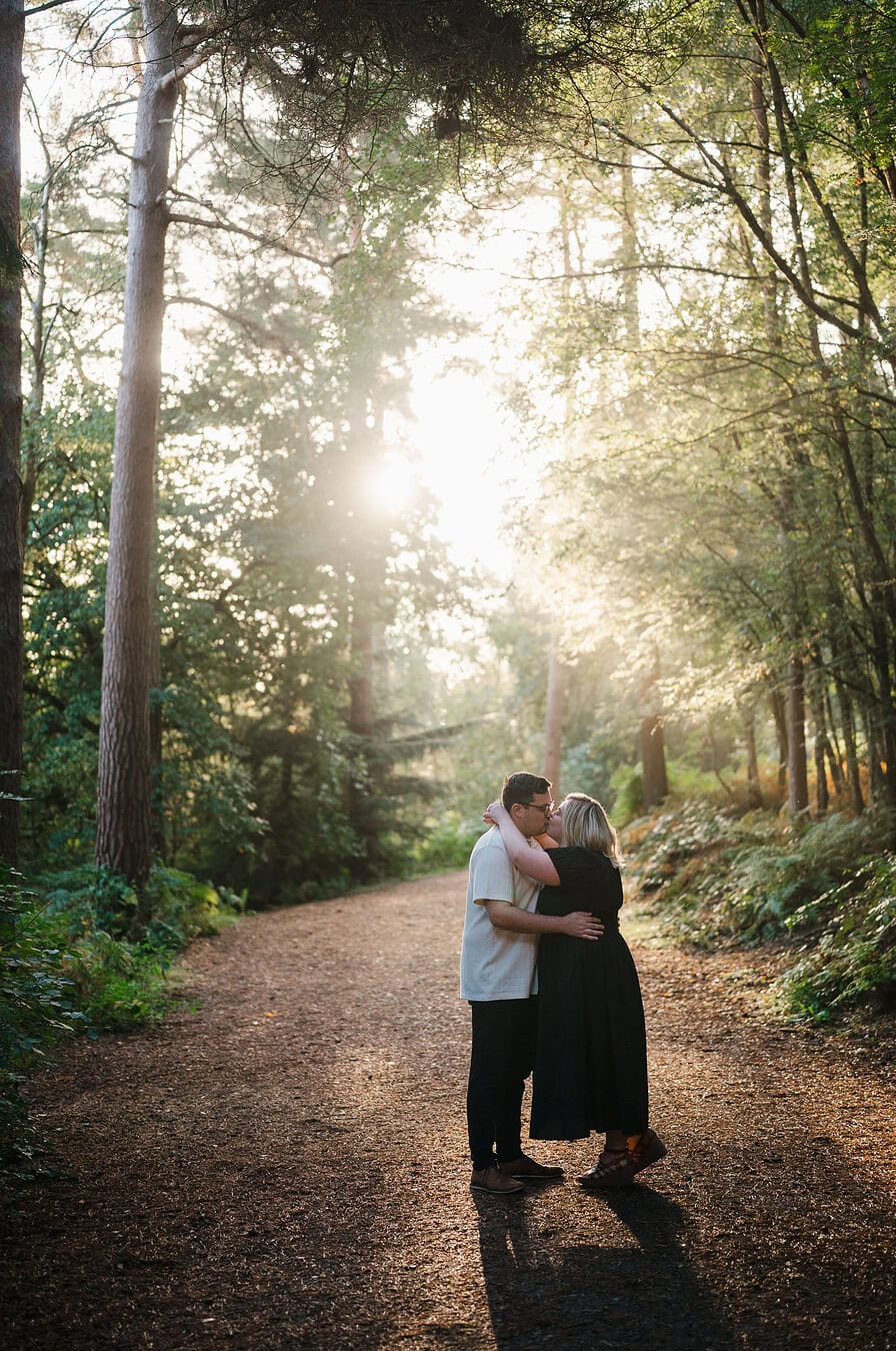 The Happy couple go for a kiss in Delamere Forest during their engagement photoshoot